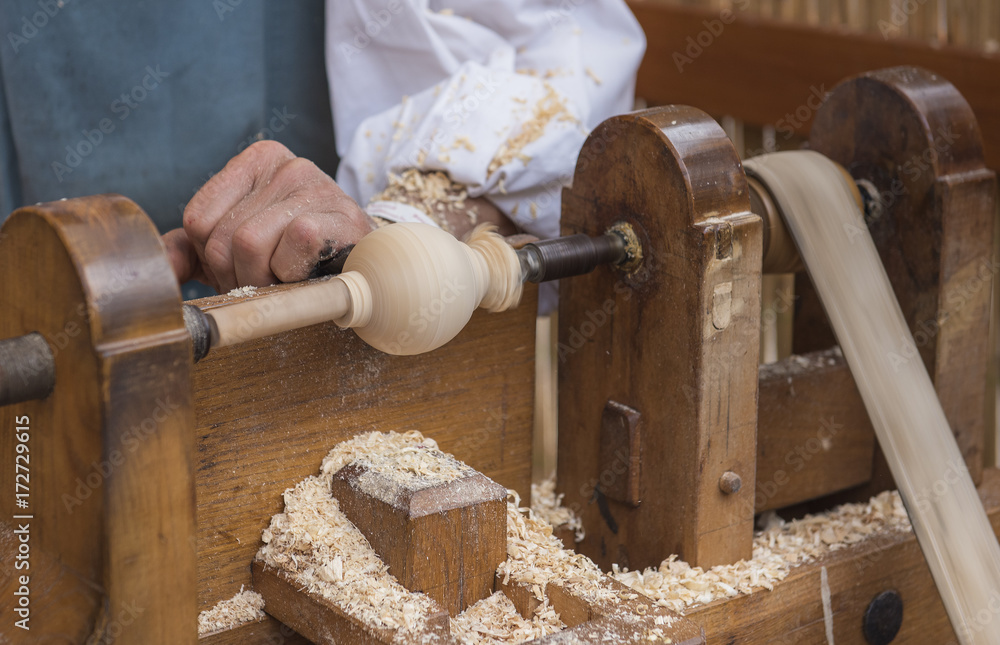 Φωτογραφία An artisan carves a piece of wood using an old manual lathe