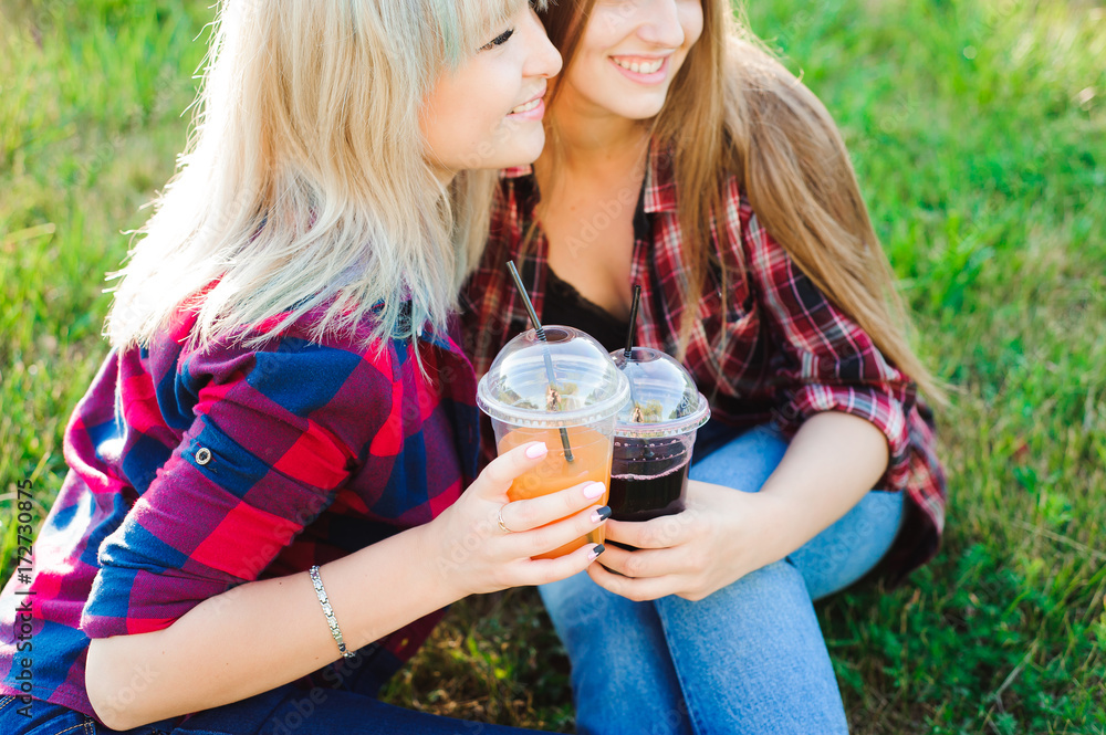 Friends drinking juice on green grass in the park Friends drinking juice on green grass in the park