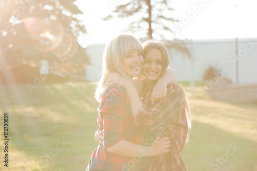 Two girls friends laughing and hugging. Hug and smile outdoor