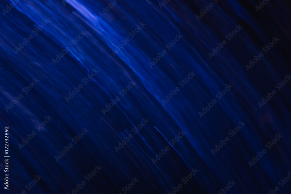 Abstract background of white and blue lines in motion on black. Bokeh of defocused curves, blurred neon leds, similar to stellar system, the Galaxy, comet and stars backdrop Abstract background of white and blue lines in motion on black. Bokeh of defocused curves, blurred neon leds, similar to stellar system, the Galaxy, comet and stars backdrop