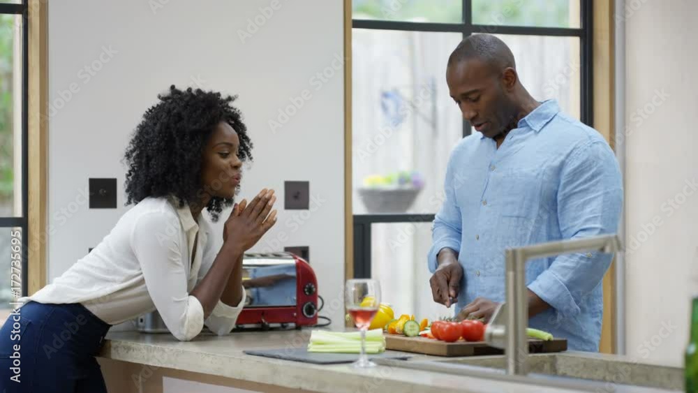 Happy couple in the kitchen at home, chatting while man prepares a meal. Happy couple in the kitchen at home, chatting while man prepares a meal.
