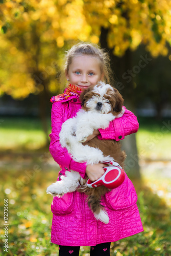 Portrait of a cute beautiful girl with a favorite pet puppy in autumn park on a background of yellow trees  