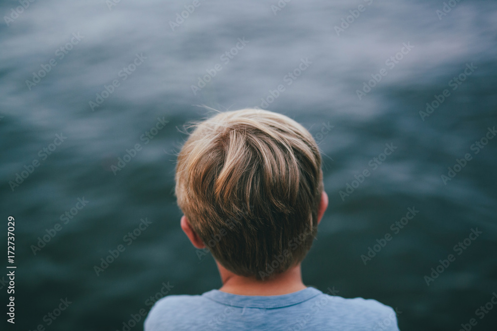 behind a boy looking out at a lake behind a boy looking out at a lake