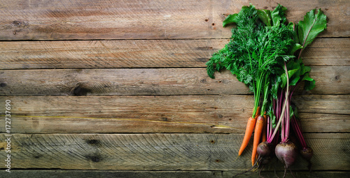 Bunch of organic freshly harvested beetroot and carrot with soil and leaves, top view. Copyspace. Concept of diet, raw, vegetarian meal. Farm, rustic and country style. Banner photo