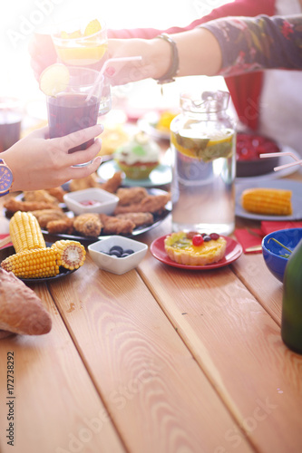 Top view of group of people having dinner together while sitting at wooden table. Food on the table. People eat fast food.