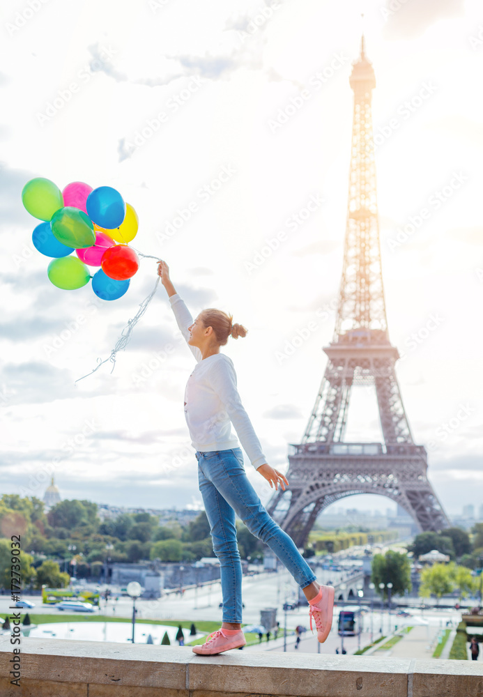 Girl with bunch of colorful balloons in Paris near the Eiffel tower.