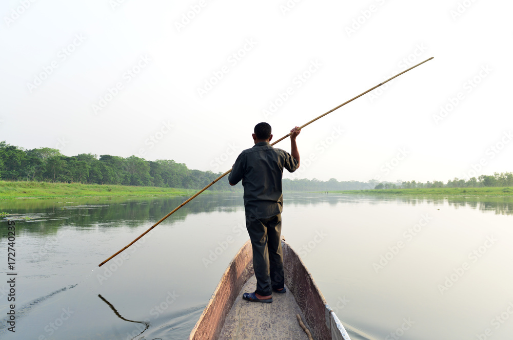 Man rowing on a boat standing up on a river Man rowing on a boat standing up on a river