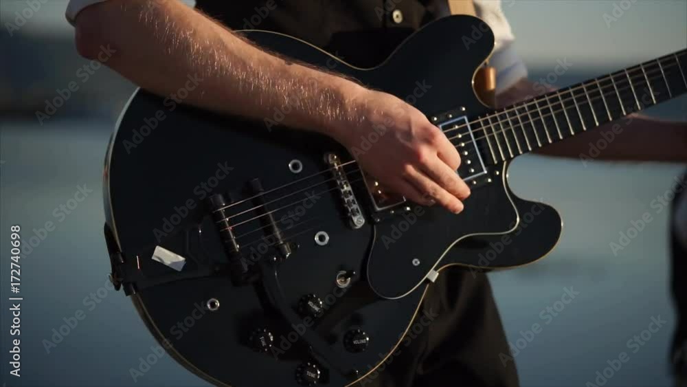 close up shot of a musical instrument, which is called a rhythm guitar, a young musician performs energetic music in the daytime in the open air