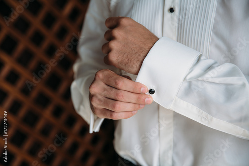 Groom hands wearing cufflinks. Elegant gentleman clother, white shirt and brown belt