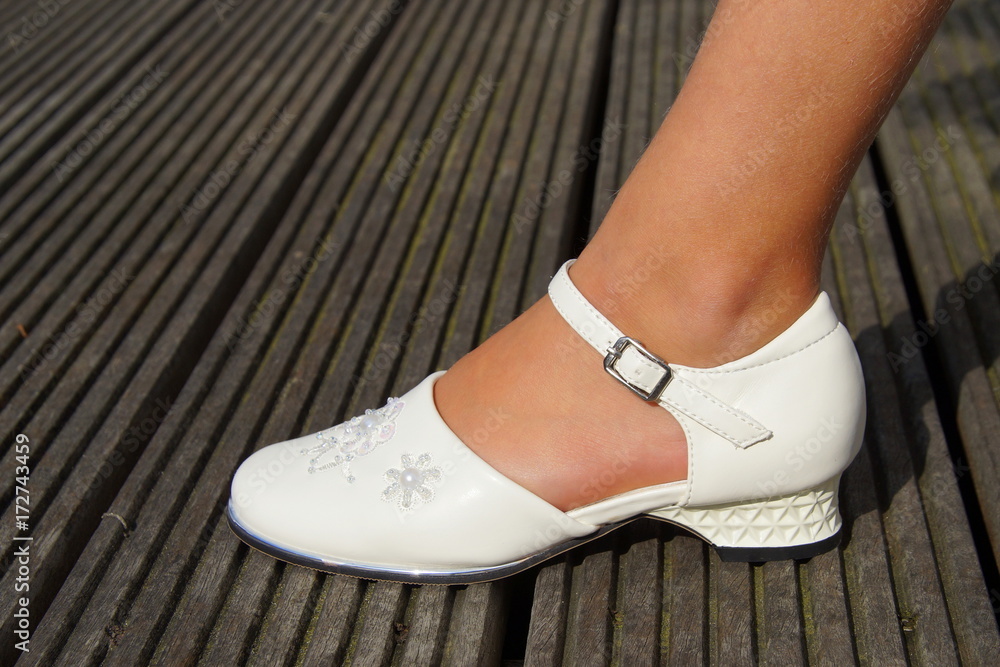 Young girl standing in a white classic wedding shoe