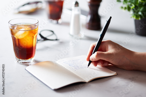 Close-up of person writing to do list with coffee on table