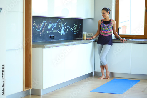 Portrait of smiling woman holding in her hand a yoga mat while standing at studio. Yoga. Woman. Wellness