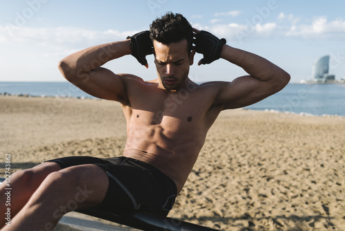 Young man doing abdominal exercises outdoors