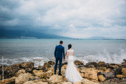 Bride and groom holding hands and turned  back view