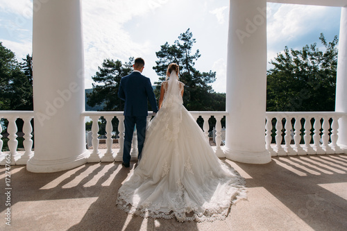Papier peint Bride and groom holding hands and turned, back view