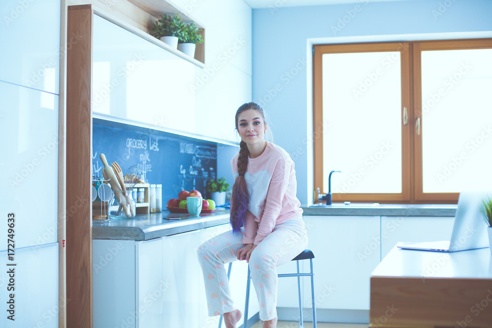 Young woman sitting on table in the kitchen. Young woman sitting on table in the kitchen.