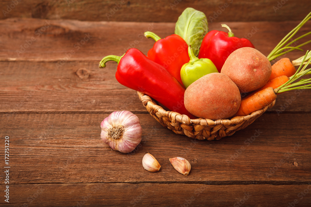Fresh vegetables, pepper, carrots, potatoes, cabbage and garlic in a basket on a wooden background. Background. Autumn, harvest. Thanksgiving Day. Space for text. Fresh vegetables, pepper, carrots, potatoes, cabbage and garlic in a basket on a wooden background. Background. Autumn, harvest. Thanksgiving Day. Space for text.