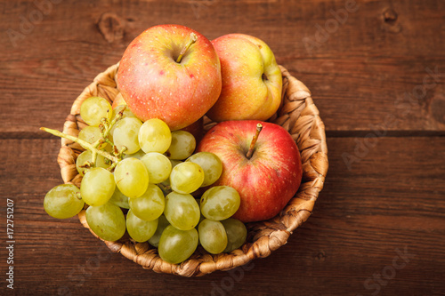 Fresh fruits  apples and a grape basket on a wooden background. Background. Autumn  harvest. Thanksgiving Day. Space for text.