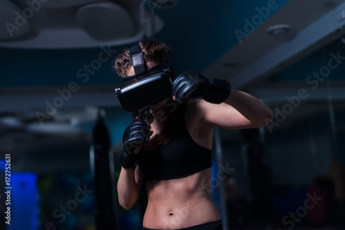 Young fighter boxer fit girl punching in VR glasses wearing boxing gloves in training. Boxing game in virtual reality 360 degrees. Futuristic gaming © Igor Kardasov