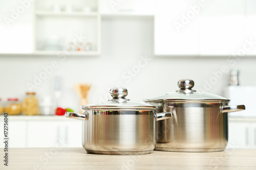 Stainless steel pots on wooden table in the kitchen