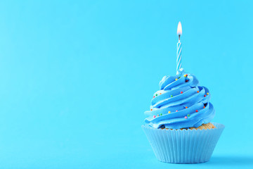Tasty cupcake with candles on a blue background