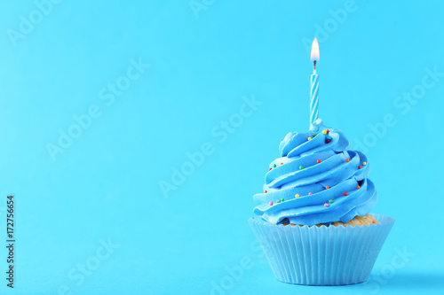 Tasty cupcake with candles on a blue background