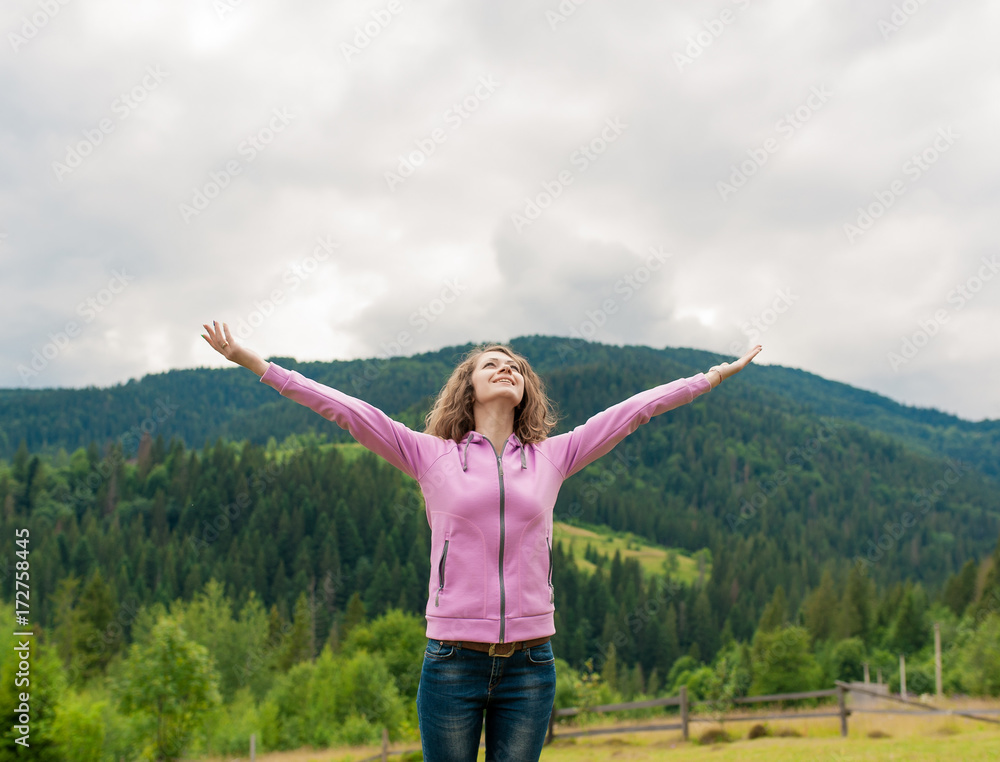 Curly woman happy smiling joyful with arms up dancing on top peak of mountains in summer during holidays. Freedom concept. Curly woman happy smiling joyful with arms up dancing on top peak of mountains in summer during holidays. Freedom concept.