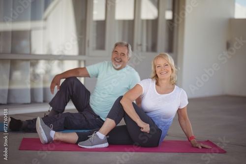 Smiling senior couple performing stretching exercise