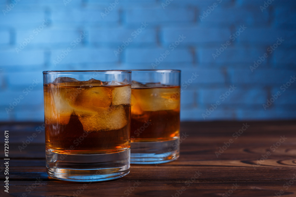 Whiskey with ice cubes on wooden table on brick wall background, copy space. Alcohol drinks, bar concept Whiskey with ice cubes on wooden table on brick wall background, copy space. Alcohol drinks, bar concept