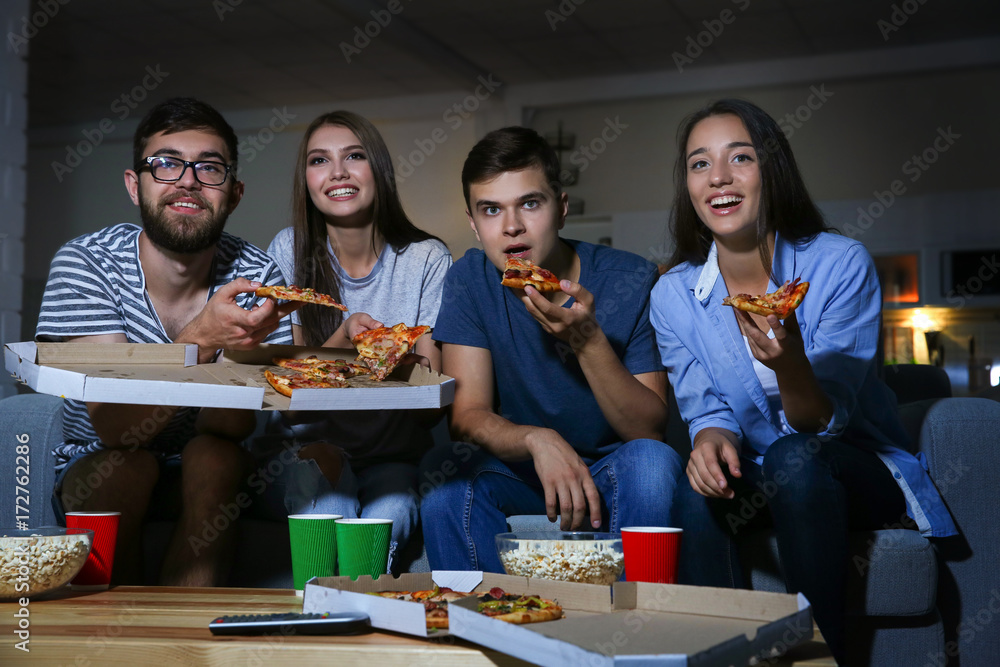 © Africa Studio - Friends watching TV in evening at home