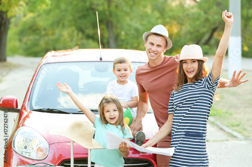 Happy family next to car in countryside