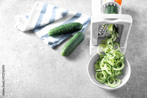 Spiral vegetable slicer with cucumber spaghetti on table