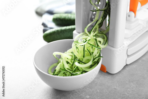 Spiral vegetable slicer with cucumber spaghetti on table photo