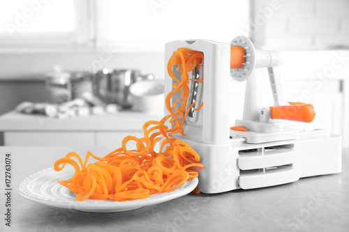 Obraz na plátně Spiral vegetable slicer with carrot spaghetti on table