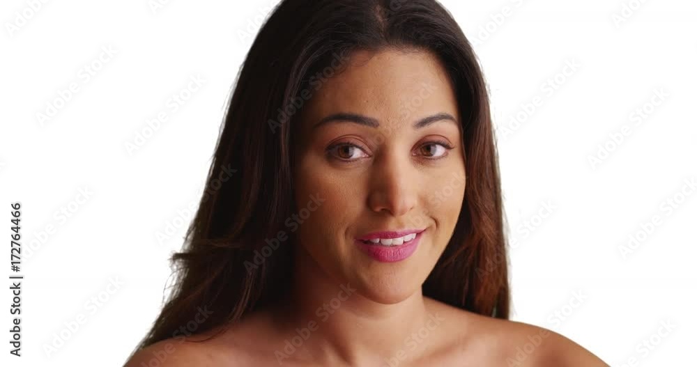 Close up of beautiful Latina female with gentle smile looking at camera on white background. Portrait of young Mexican woman's head and bare shoulders in studio. 4k Close up of beautiful Latina female with gentle smile looking at camera on white background. Portrait of young Mexican woman's head and bare shoulders in studio. 4k