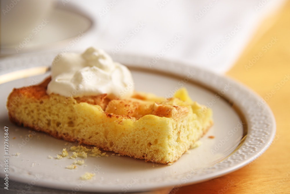 piece of homemade apple cake with whipped cream on a white plate, close up, copy space piece of homemade apple cake with whipped cream on a white plate, close up, copy space