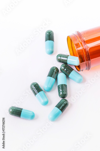 Blue pills an pill bottle on white background