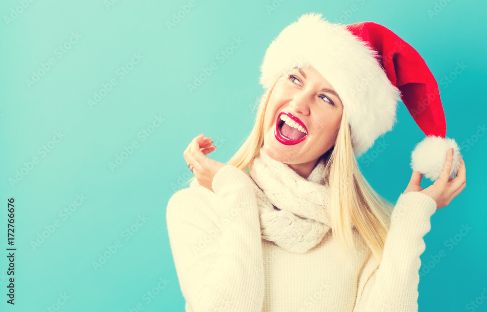 Happy young woman with Santa hat on a blue background Happy young woman with Santa hat on a blue background
