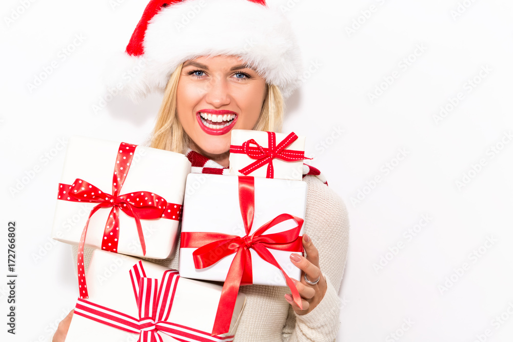 Happy young woman with Santa hat holding a stack of gift boxes Happy young woman with Santa hat holding a stack of gift boxes
