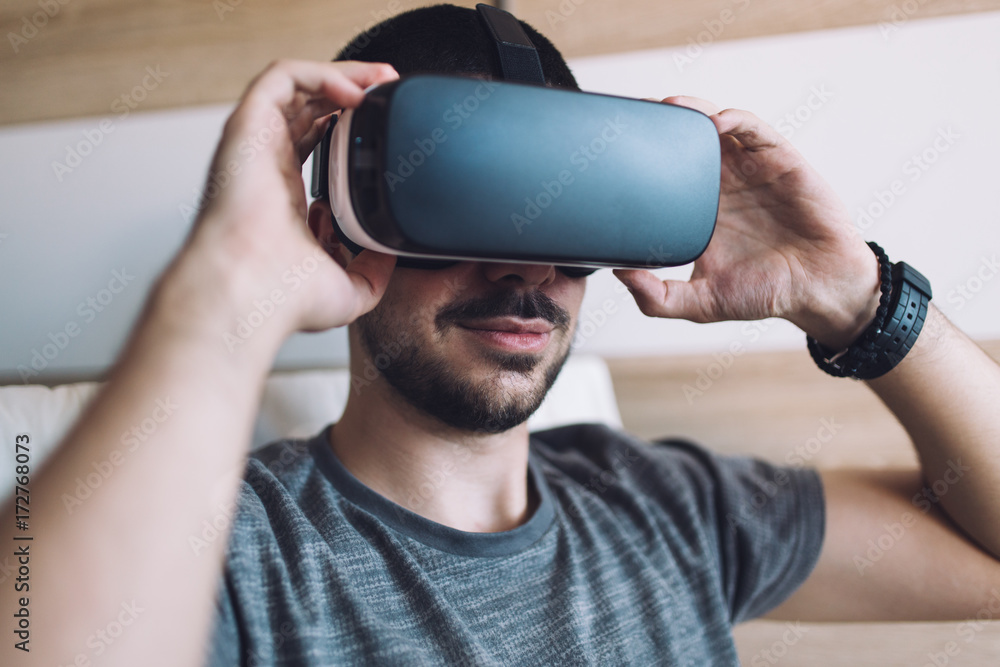 Young bearded man enjoying virtual reality at his home. Young bearded man enjoying virtual reality at his home.