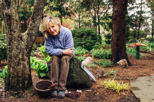 Baby Boomer gardening woman resting on a stone photo