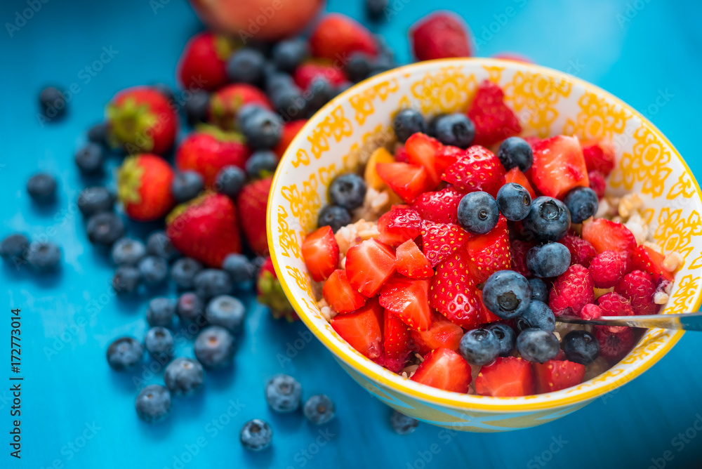 Ceramic bowl with blueberries, strawberries and blackberries on blue background. Close up Ceramic bowl with blueberries, strawberries and blackberries on blue background. Close up