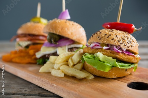 Various burgers with Frenc fries on cutting board photo