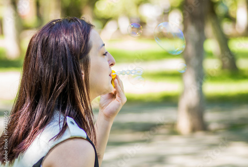 caucasian woman blowing soap bubbles in the park