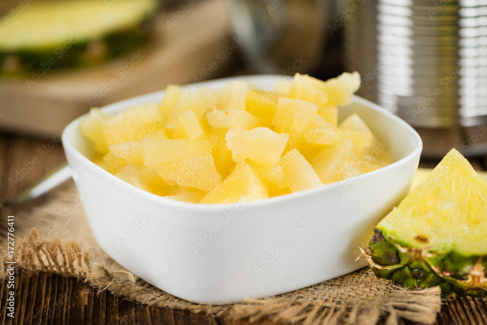 Chopped Pineapple (preserved) on wooden background; selective focus Chopped Pineapple (preserved) on wooden background; selective focus
