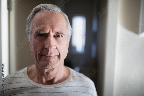 Close-up portrait of senior male patient standing in corridor photo