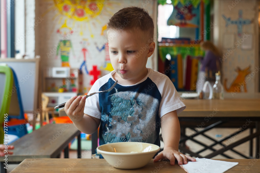 Cute toddler boy eating at indoors restaurant. Healthy/unhealthy food for little kids Cute toddler boy eating at indoors restaurant. Healthy/unhealthy food for little kids