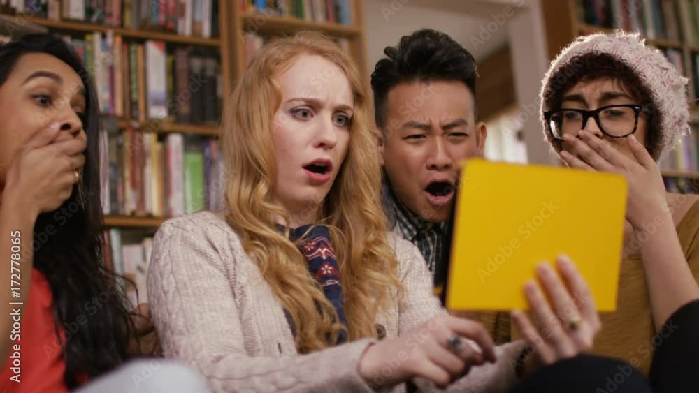 Student friends in shared accommodation reacting to something they see on tablet computer. Student friends in shared accommodation reacting to something they see on tablet computer.
