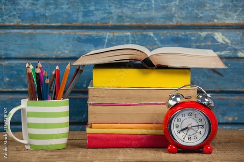 Stack of books, alarm clock and pen holder