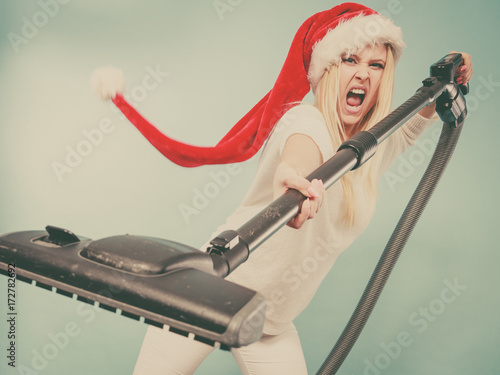 Angry girl in santa helper hat with vacuum cleaner photo